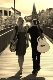 Mary und Punky von hinten auf einer Fußgängerbrücke, beide tragen ihre Gitarren auf dem Rücken